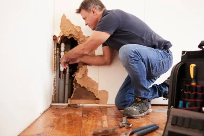 Emergency water damage repair — opening the wall to reach the source