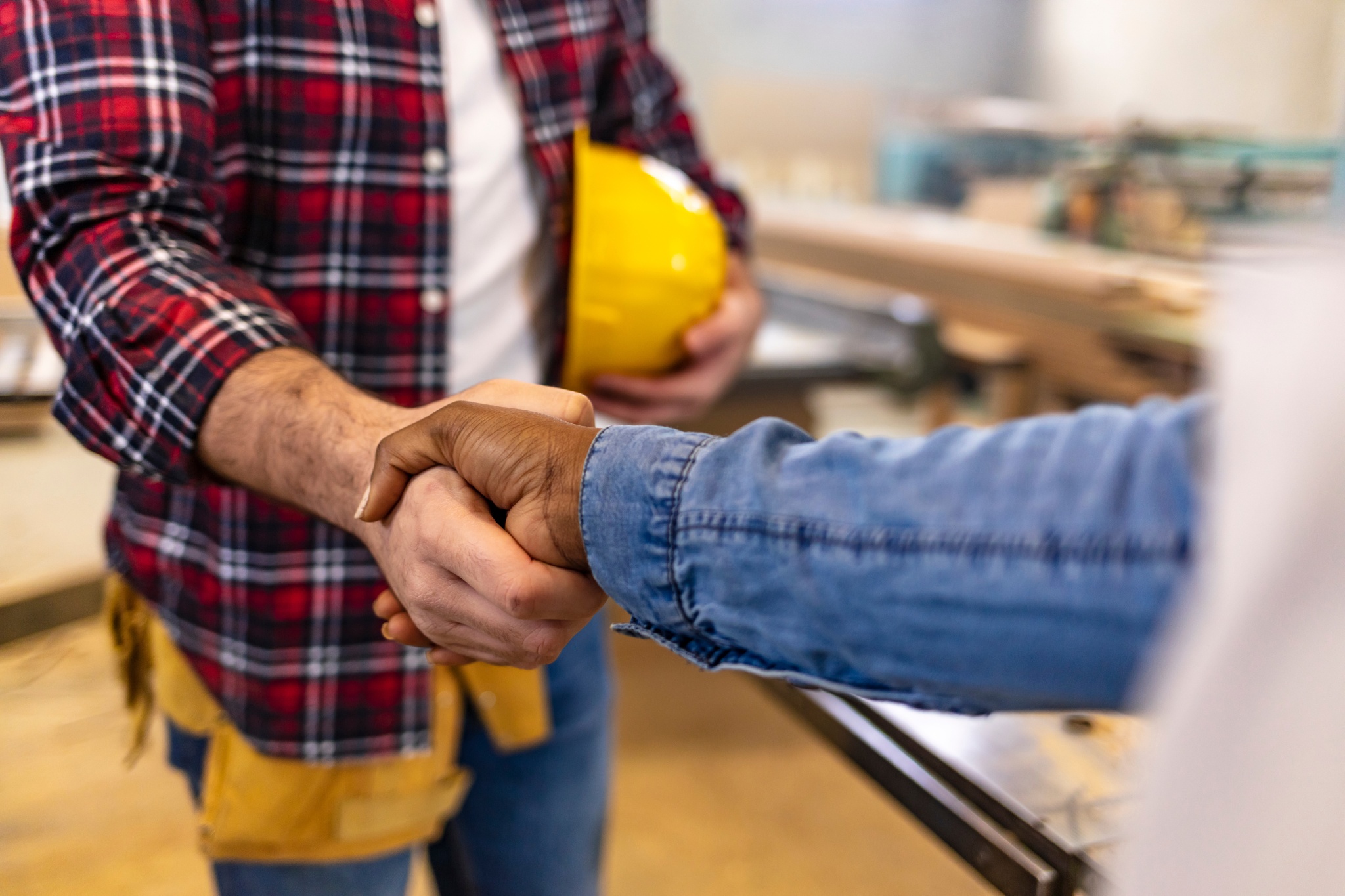 Affordable general contractors shake hands in a workshop during a project consultation