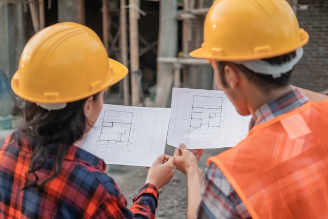 Construction workers reviewing blueprints at a commercial site during daylight hours