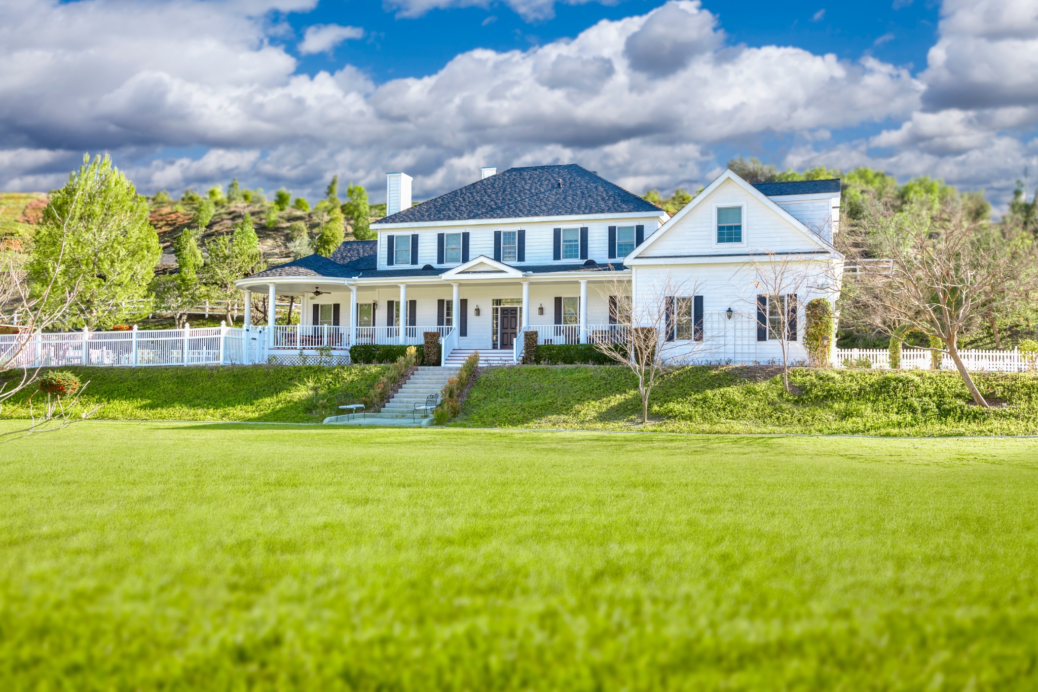 Custom home floor plans for a picturesque rural residence with expansive greenery and dramatic skies