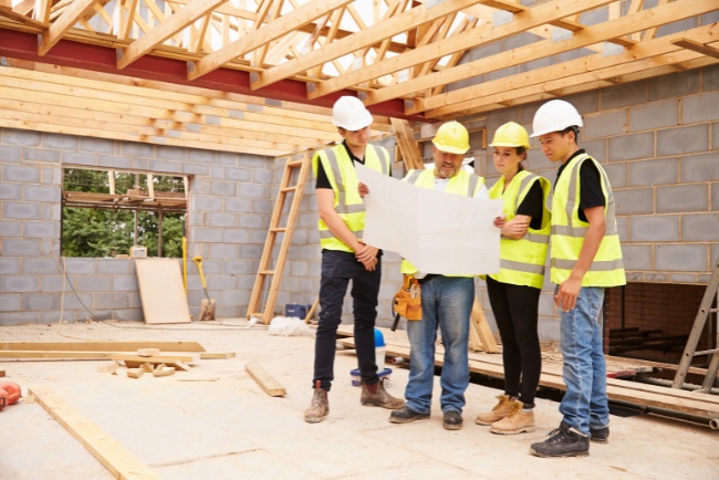 Construction team reviews blueprints on site during residential project in the afternoon