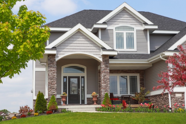 Modern custom home design with landscaped garden and welcoming entryway in residential neighborhood