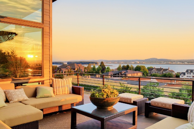 Modern patio features a scenic sunset view over the lake with cozy seating for relaxation