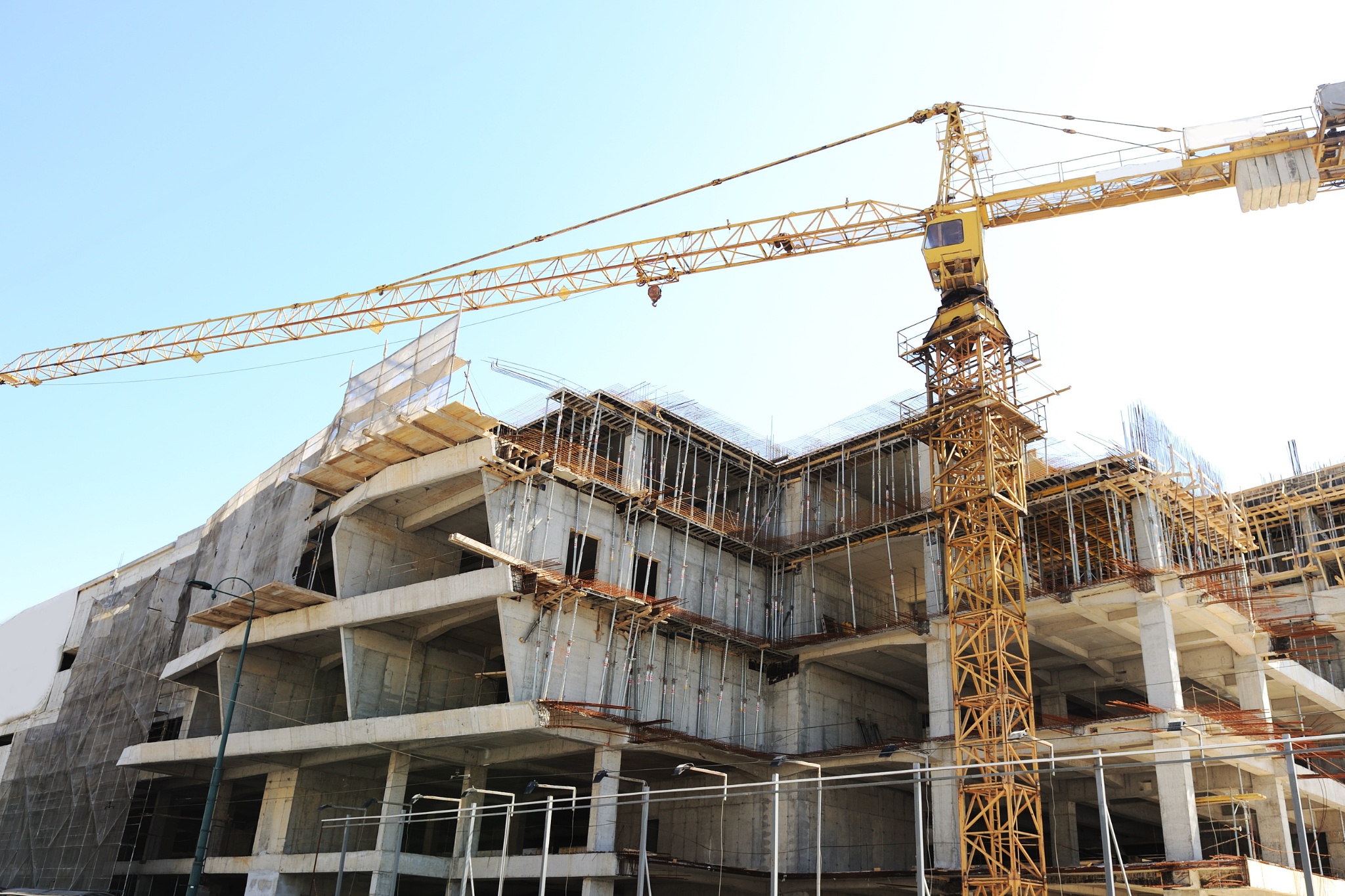 Construction of modern office space featuring a crane and scaffold structures in a bustling urban environment