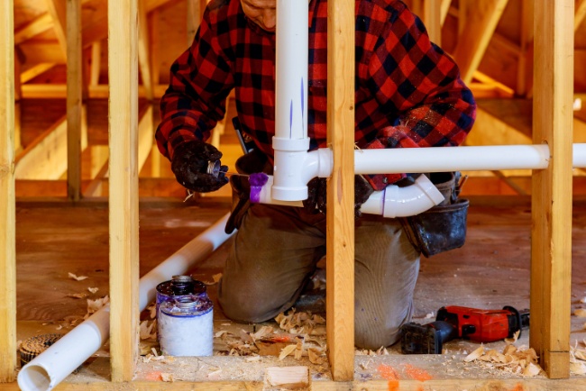 Expert plumber installing PVC piping in a construction site for effective drainage and plumbing solutions