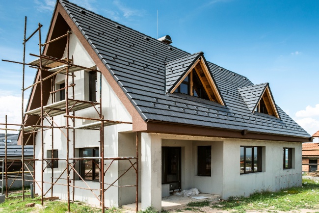 Residential construction project showcasing a modern house with scaffolding on a clear sunny day