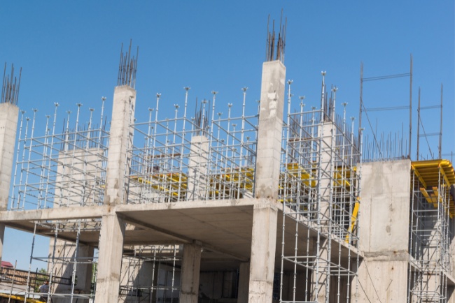 Construction site showcases retrofitting techniques with scaffolding under clear blue sky