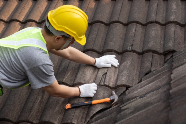 Professional roofing service repairing tiles on a residential roof during daylight