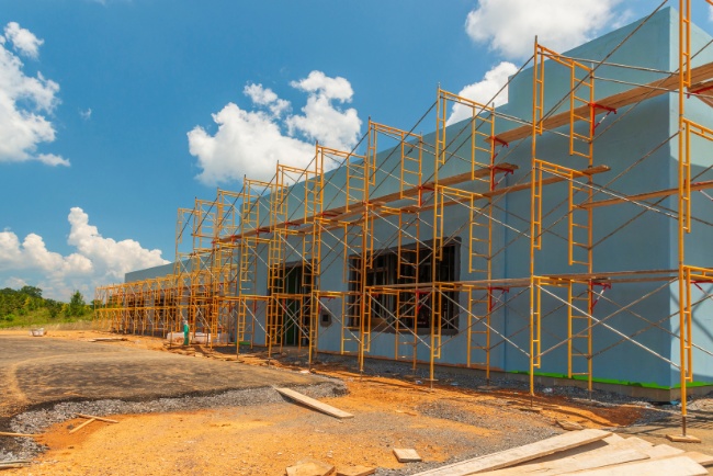 Retrofit project underway at construction site with scaffolding under clear blue sky